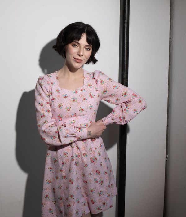 Woman holding a graceful yoga pose in a dark room with pink light.